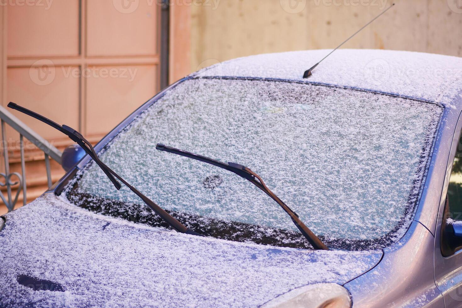 Snow covers car windshield in a quiet urban street during winter photo