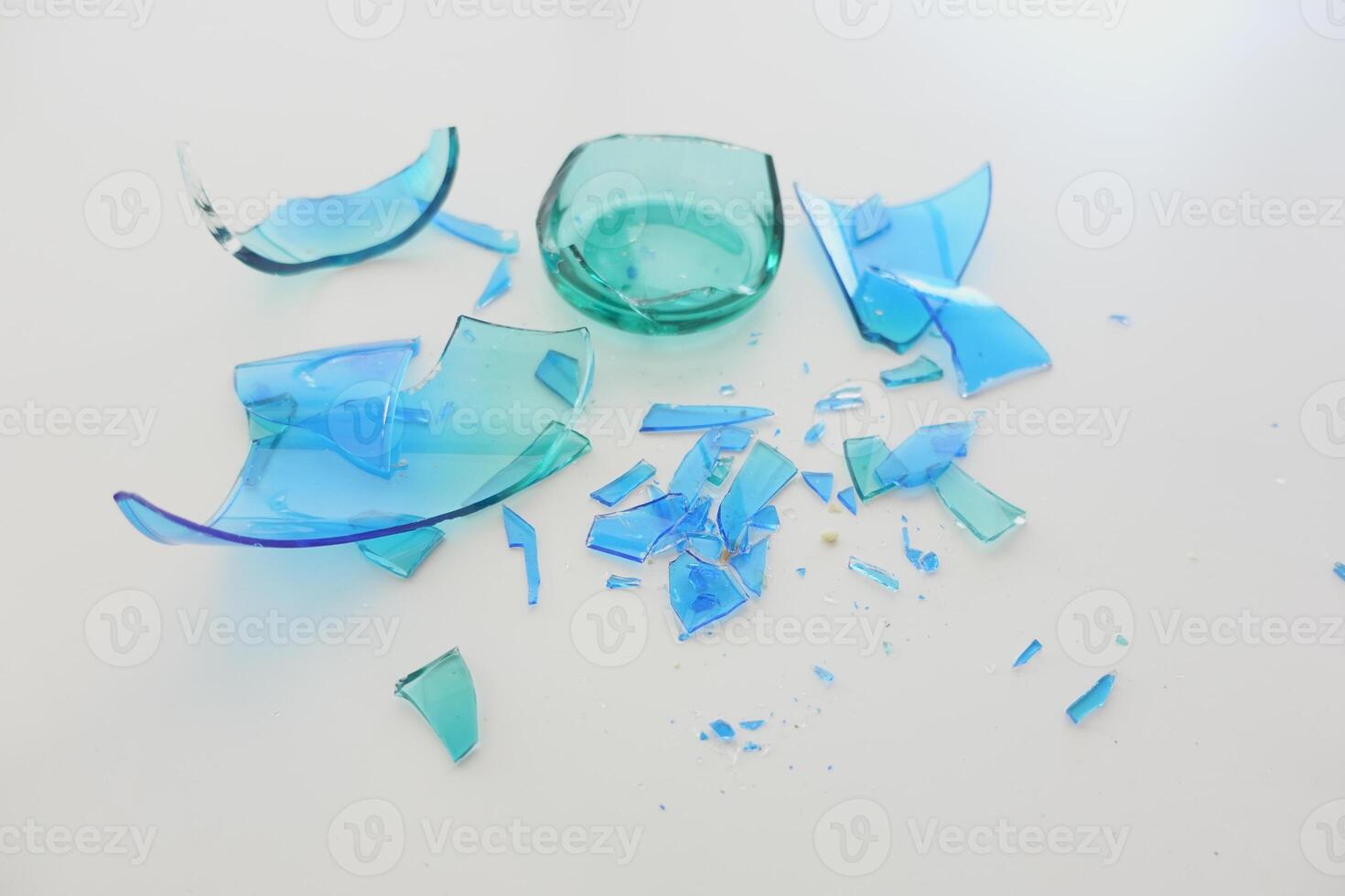 Fragments of colored glass scattered on a white surface after breaking photo