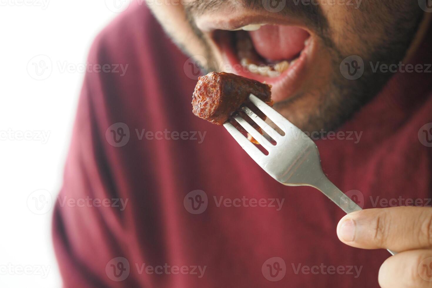 Enjoying a flavorful bite of sausage at a cozy dining setting photo