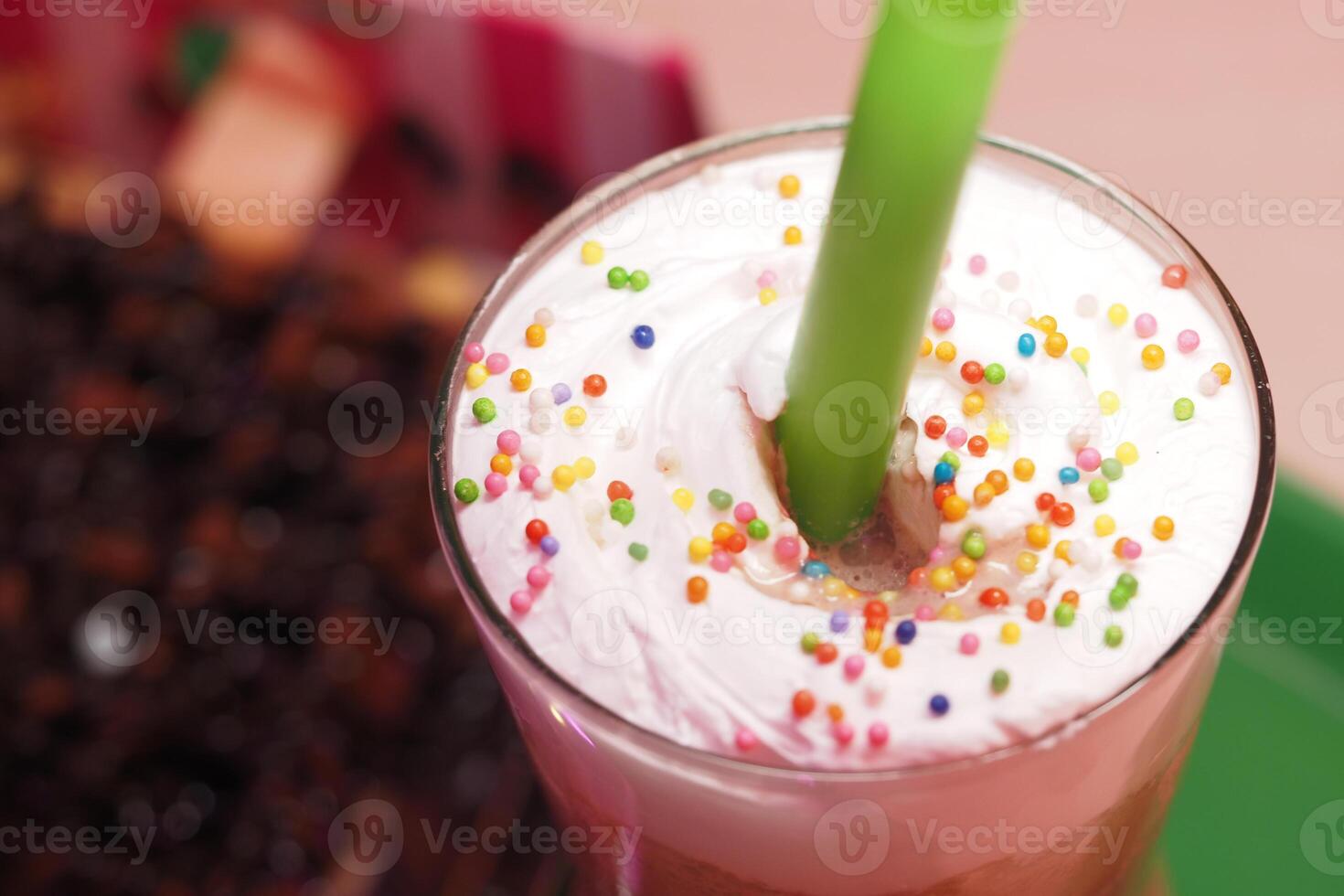 Colorful dessert drink topped with cream and sprinkles in cafe setting photo