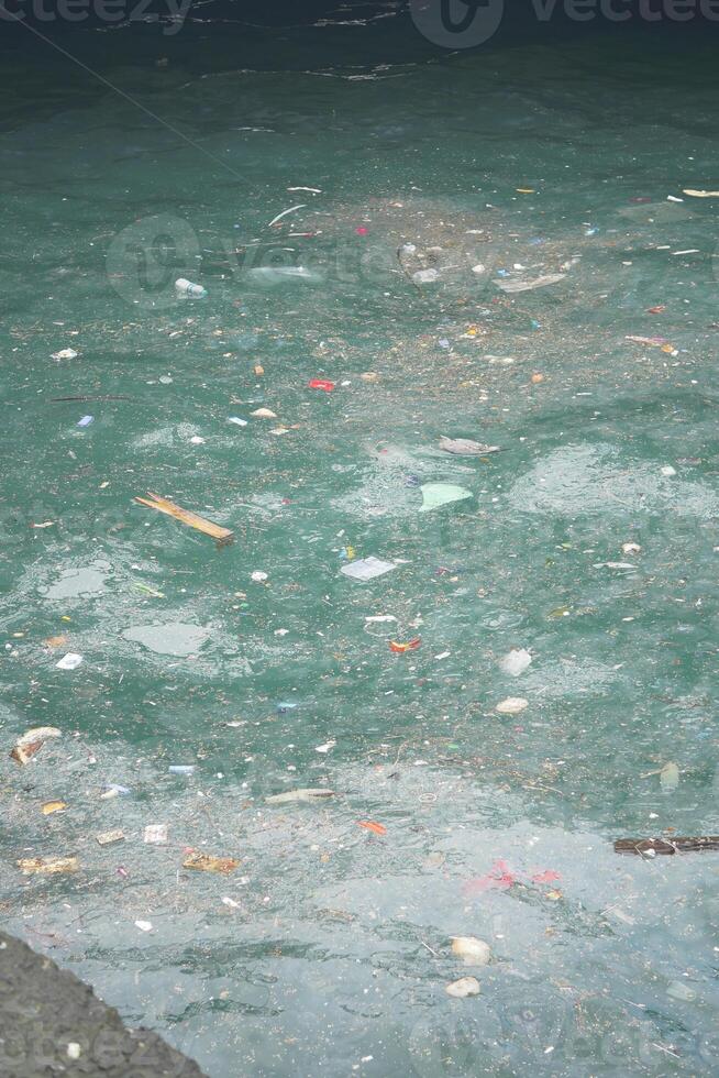 Pollution seen in a water body with garbage and debris floating photo