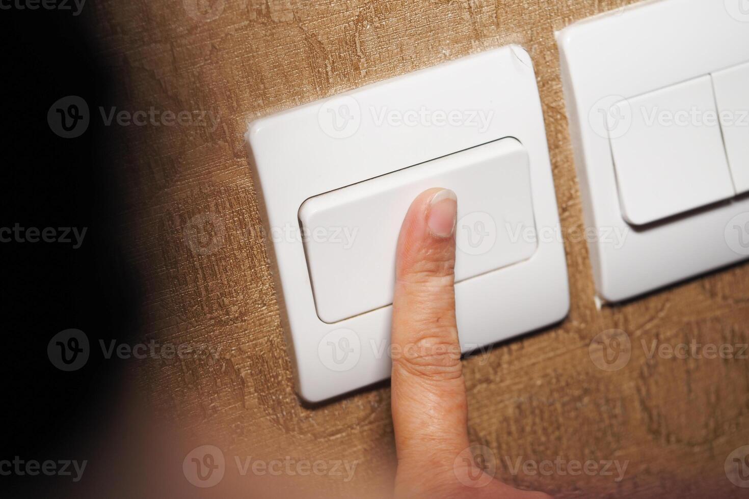 Person turning off the light switch in a home environment photo