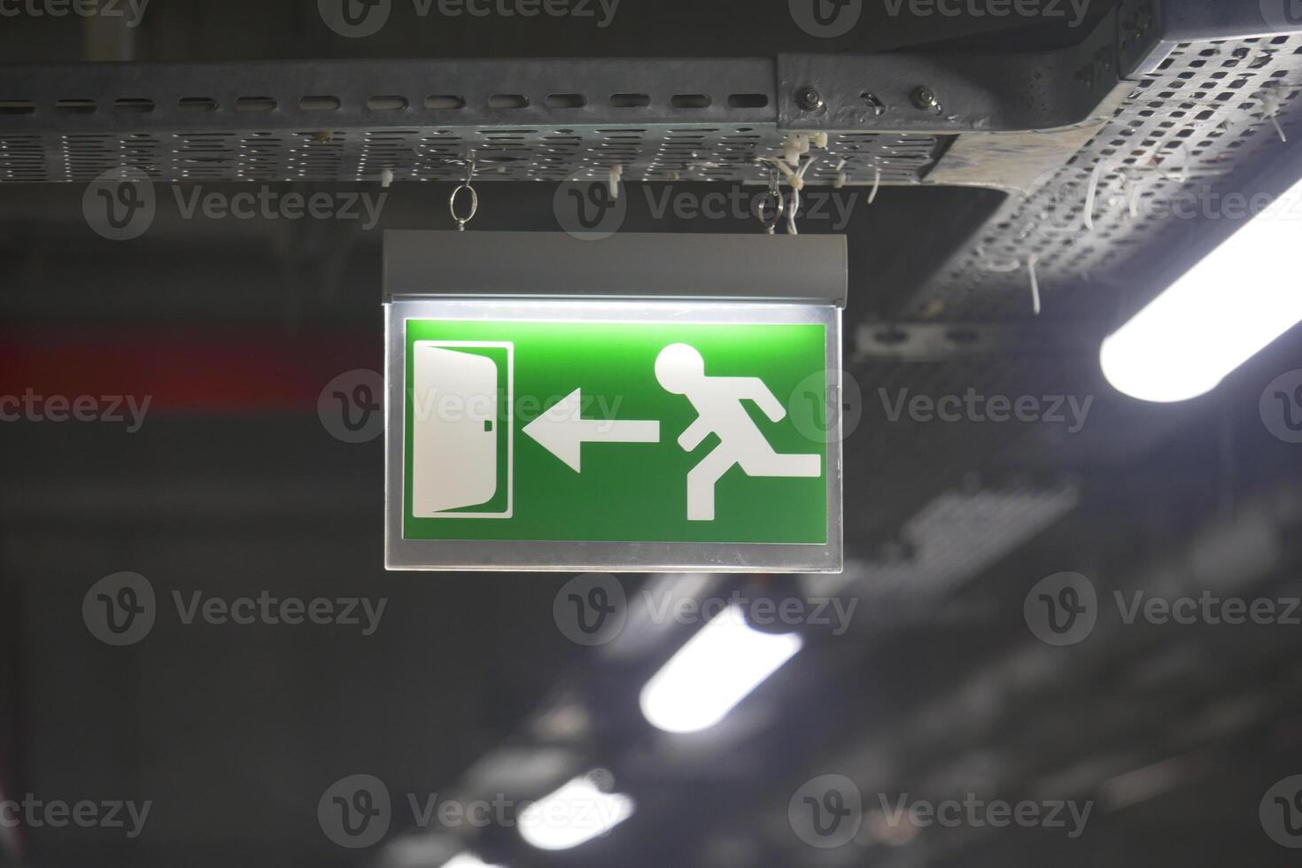 Emergency exit sign illuminated in a dimly lit building corridor photo