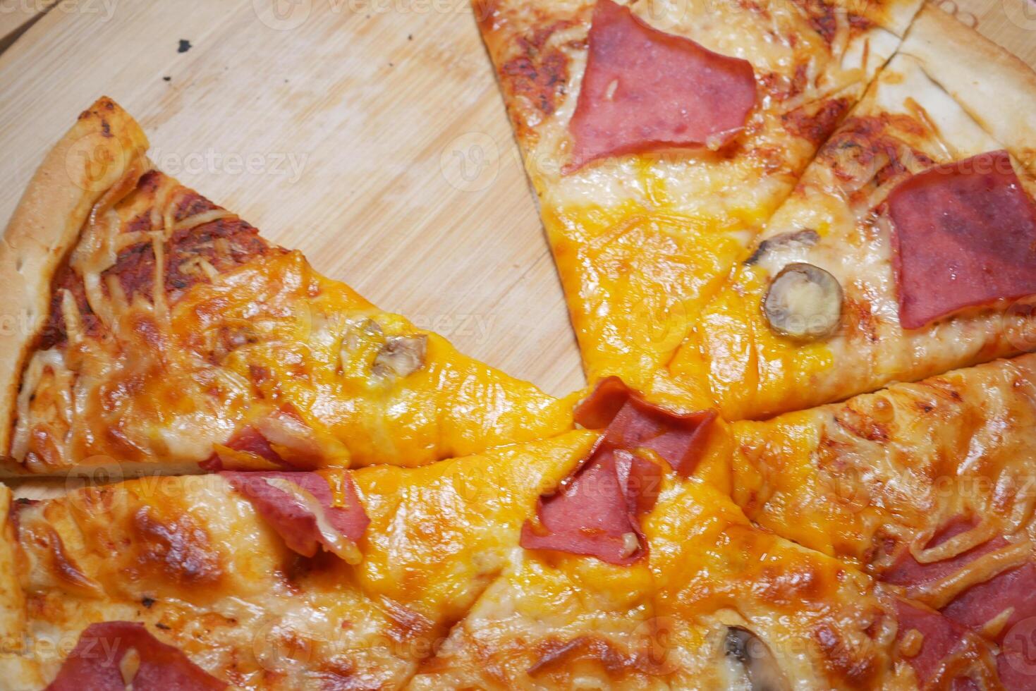 Slices of pizza topped with ham and cheese on a wooden board photo