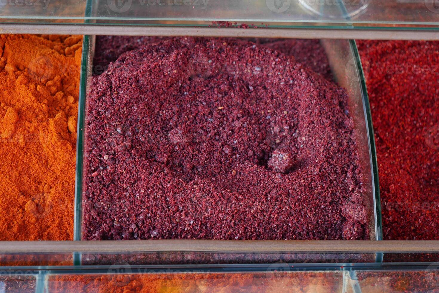 Colorful spices arranged in clear containers at a market stall photo