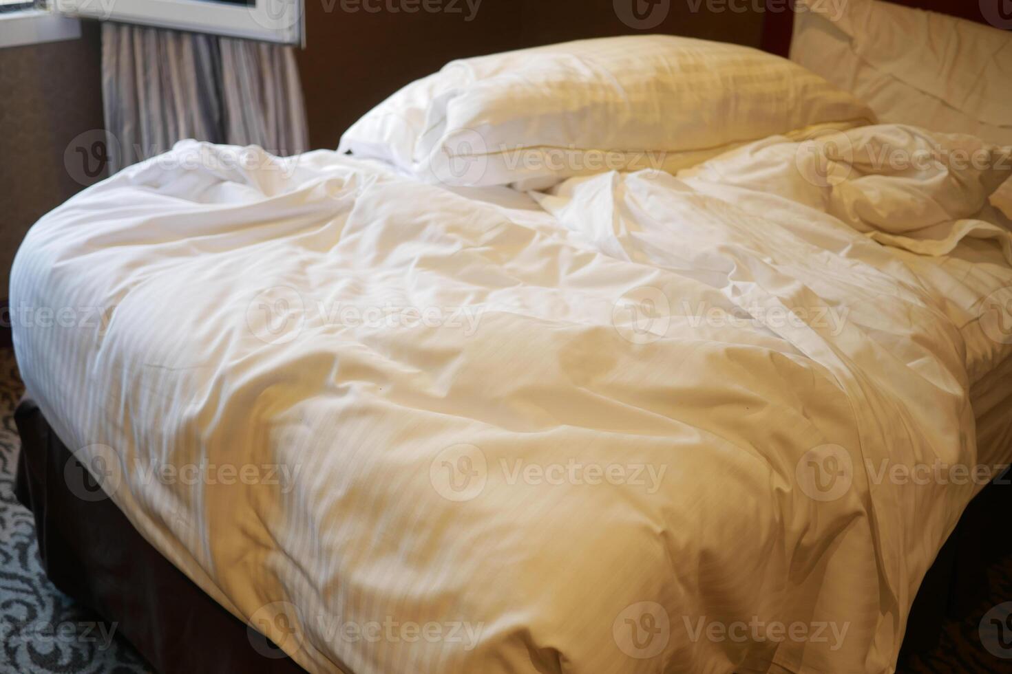 messy bed with crumpled bedding and soft pillows photo
