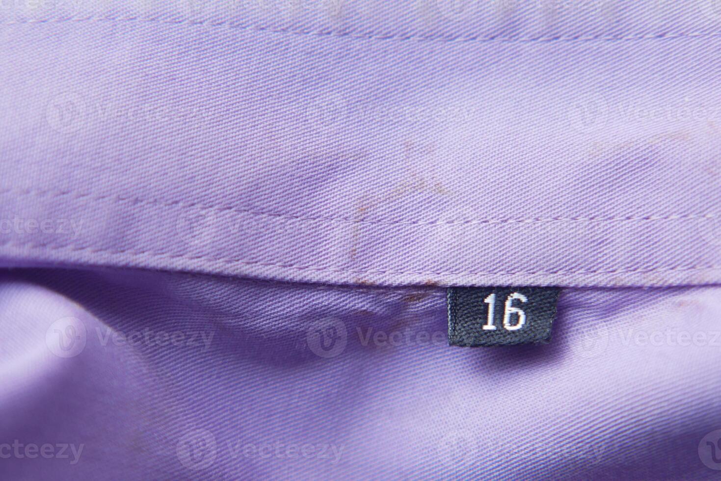 Number tag on a lilac fabric near the neckline of a garment photo