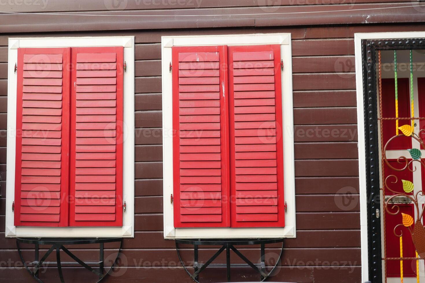 Red shutters on a brown wall add character to the design photo