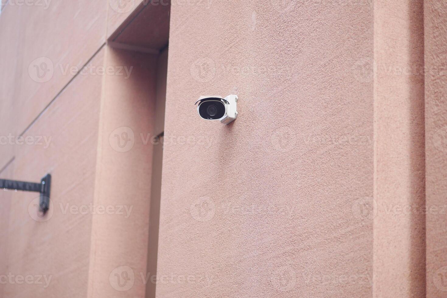 Security camera mounted on a decorative wall in an urban area photo