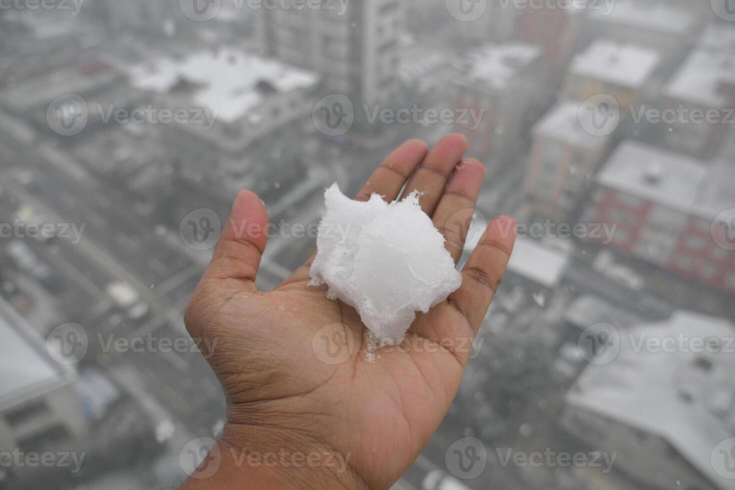 Snowball in palm during urban snowstorm on a winter day photo