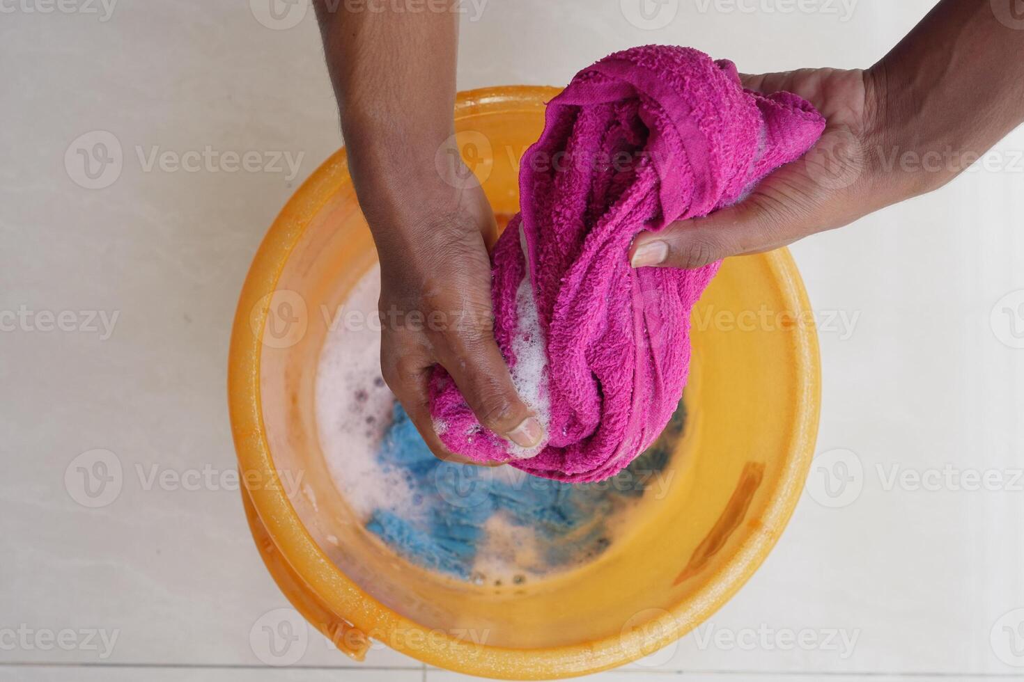 Mixing cleaning solutions while washing a pink cloth in a bucket photo