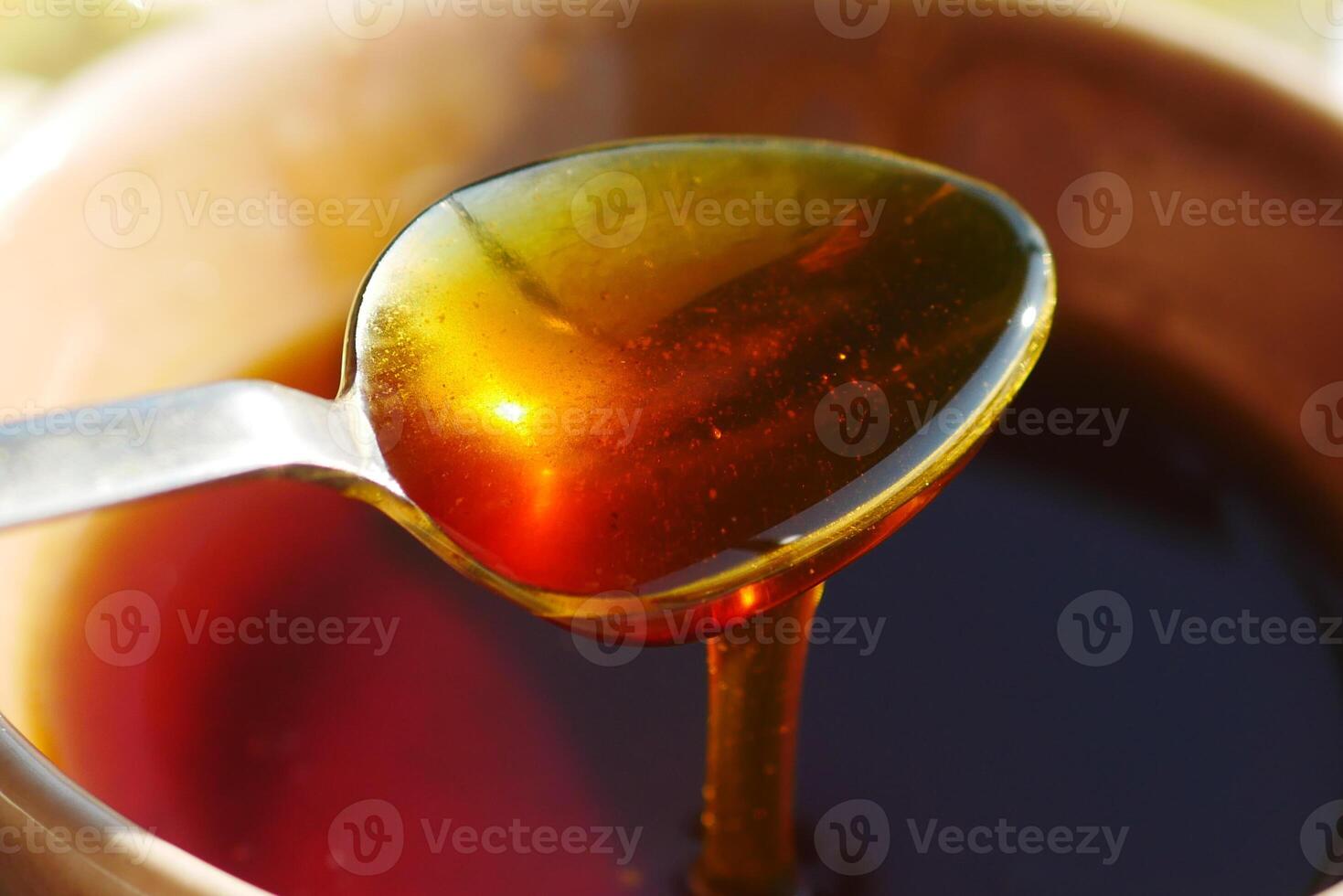 Golden honey dripping from a spoon in natural light photo