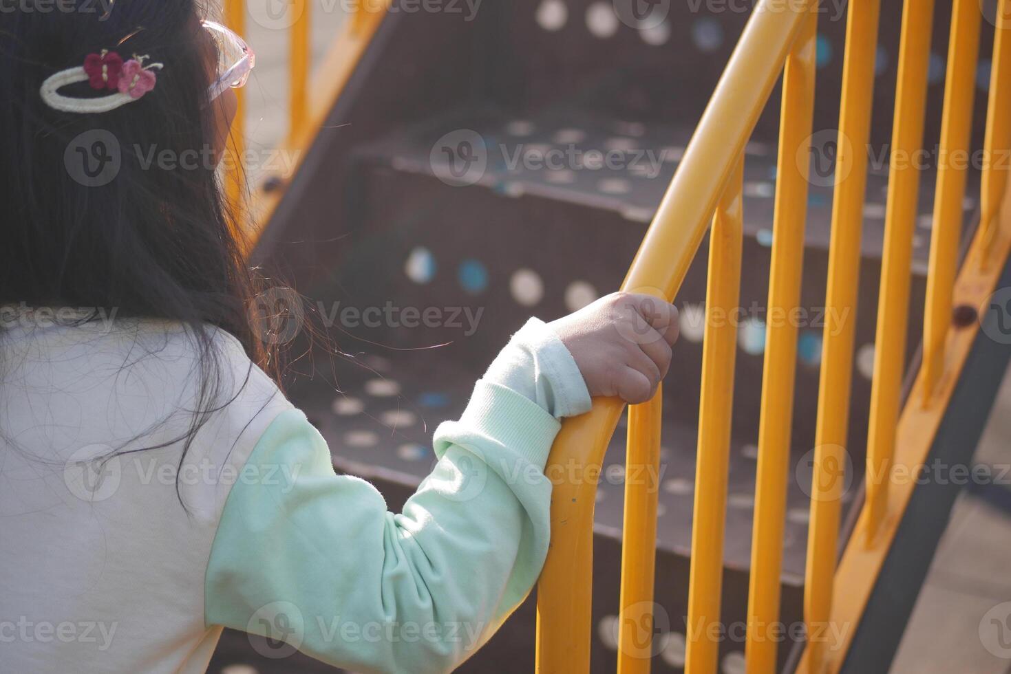 Child climbing brightly colored playground steps in sunlight photo
