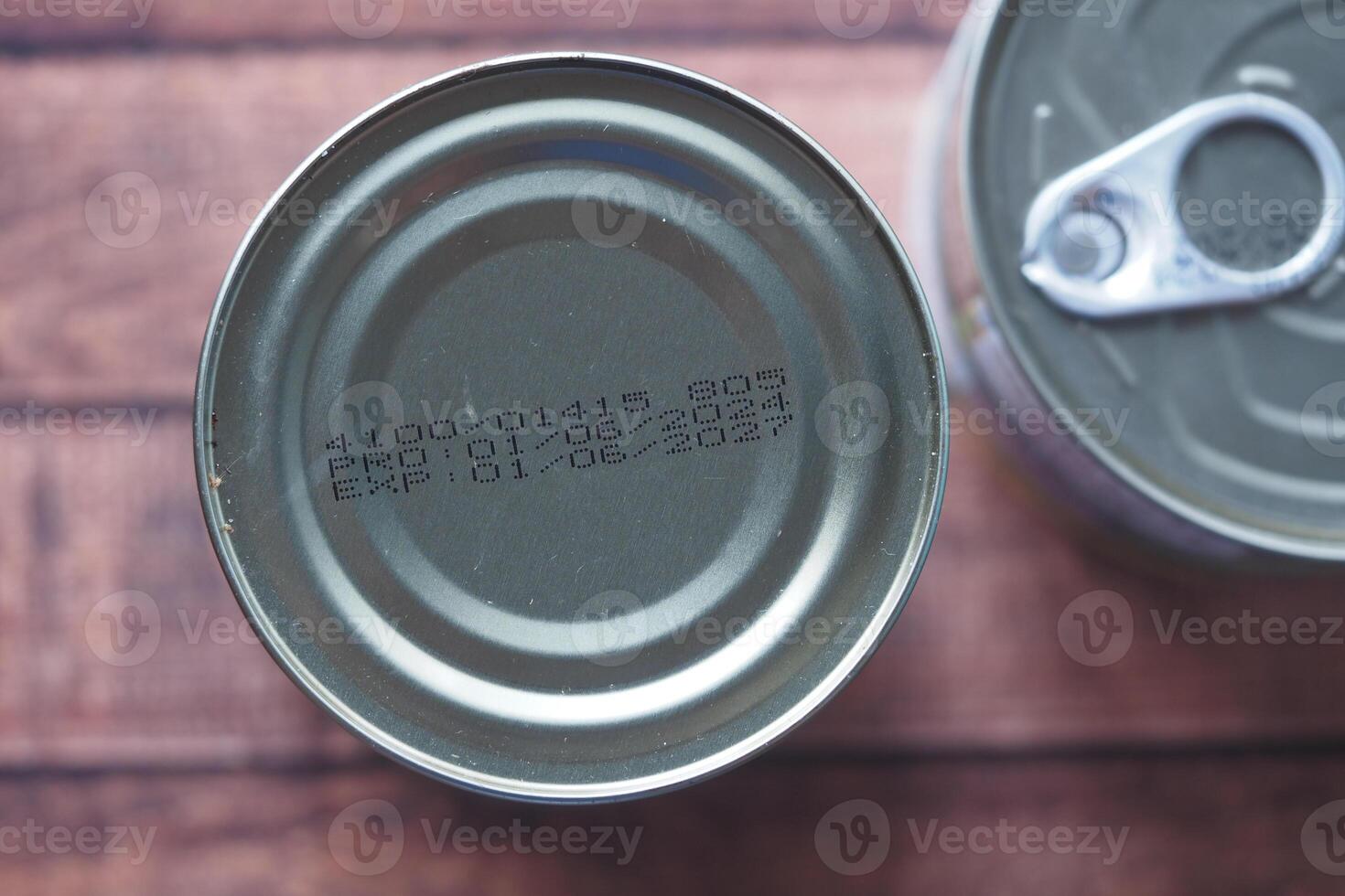 Cans with expiration dates and production codes on wooden surface photo
