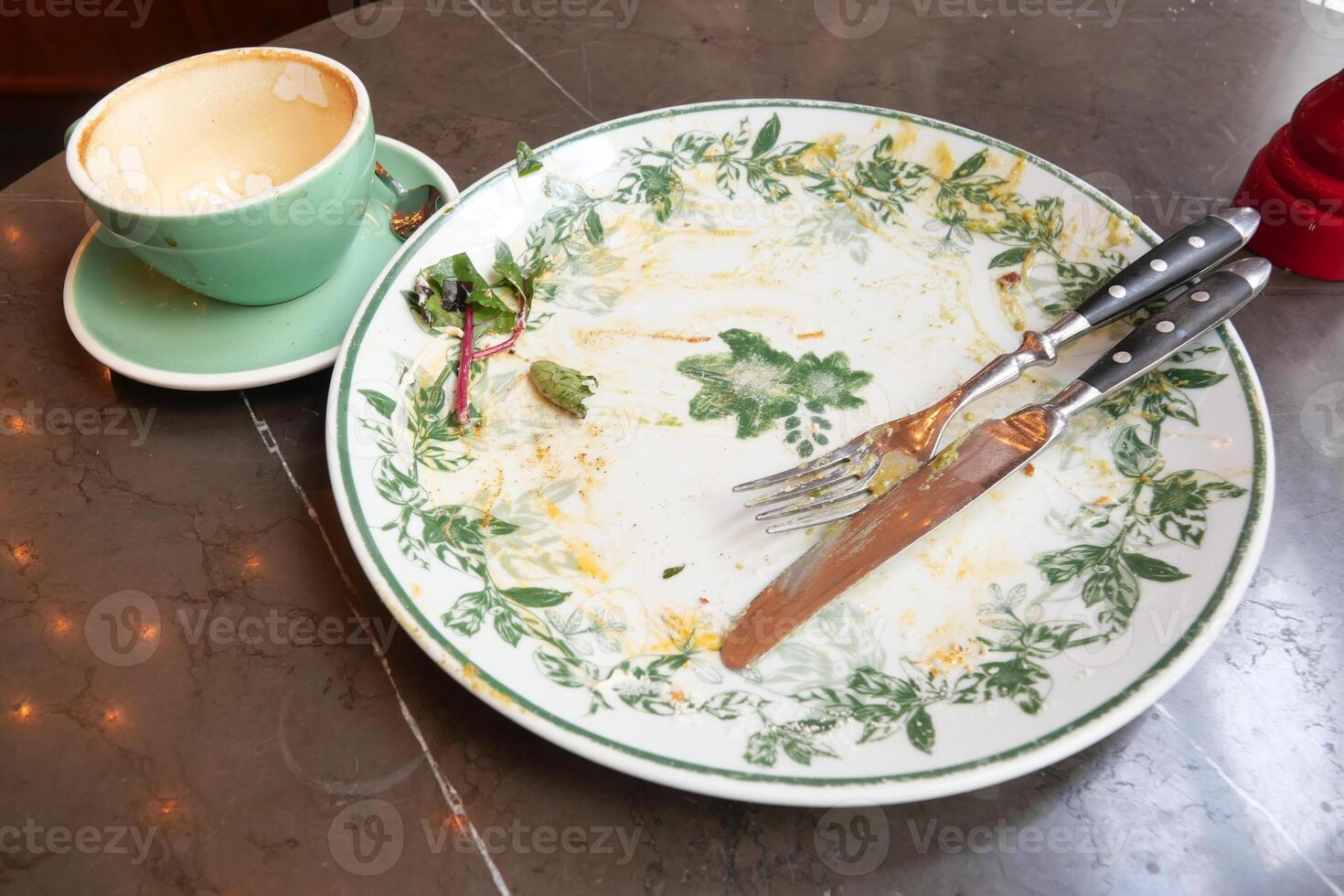 Empty plate and cup on a marble table after a meal at a cafe photo