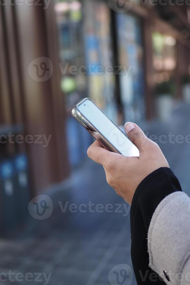 Person holding smartphone while walking in urban area photo