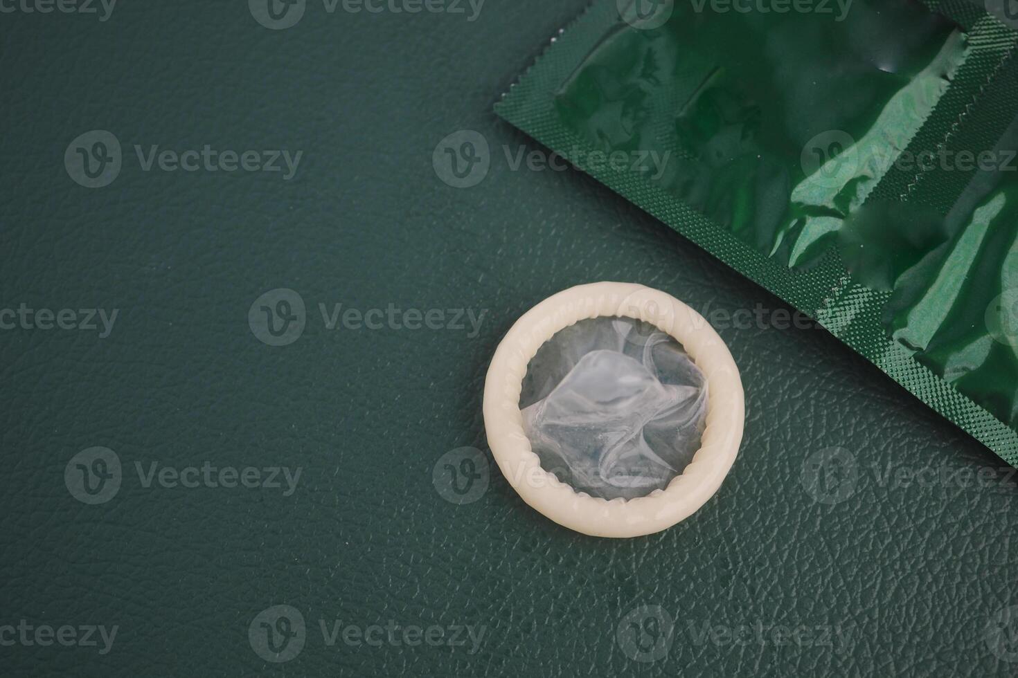 Condom placed on a textured surface beside its protective packaging photo