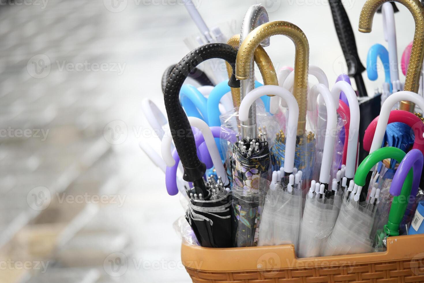 Colorful umbrellas displayed in a basket during rainy weather photo