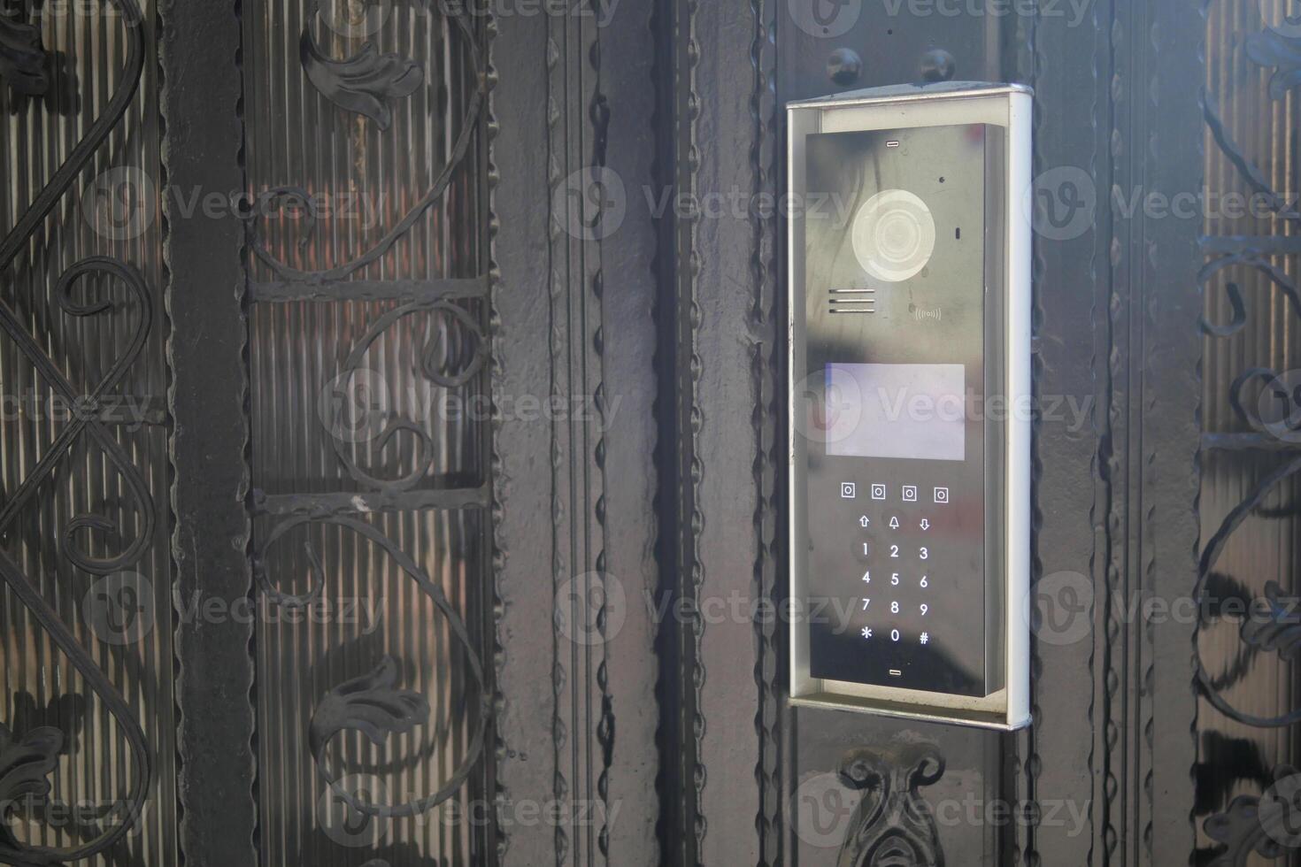 Modern intercom system mounted on an ornate black gate photo