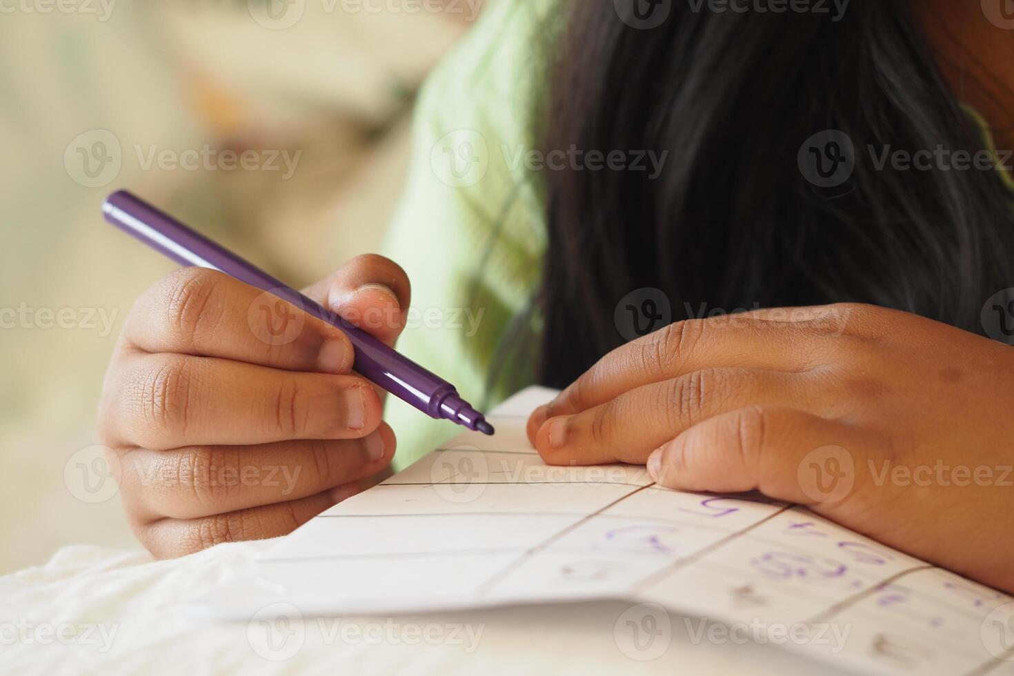 Child writing notes with a purple pen on a cozy surface photo