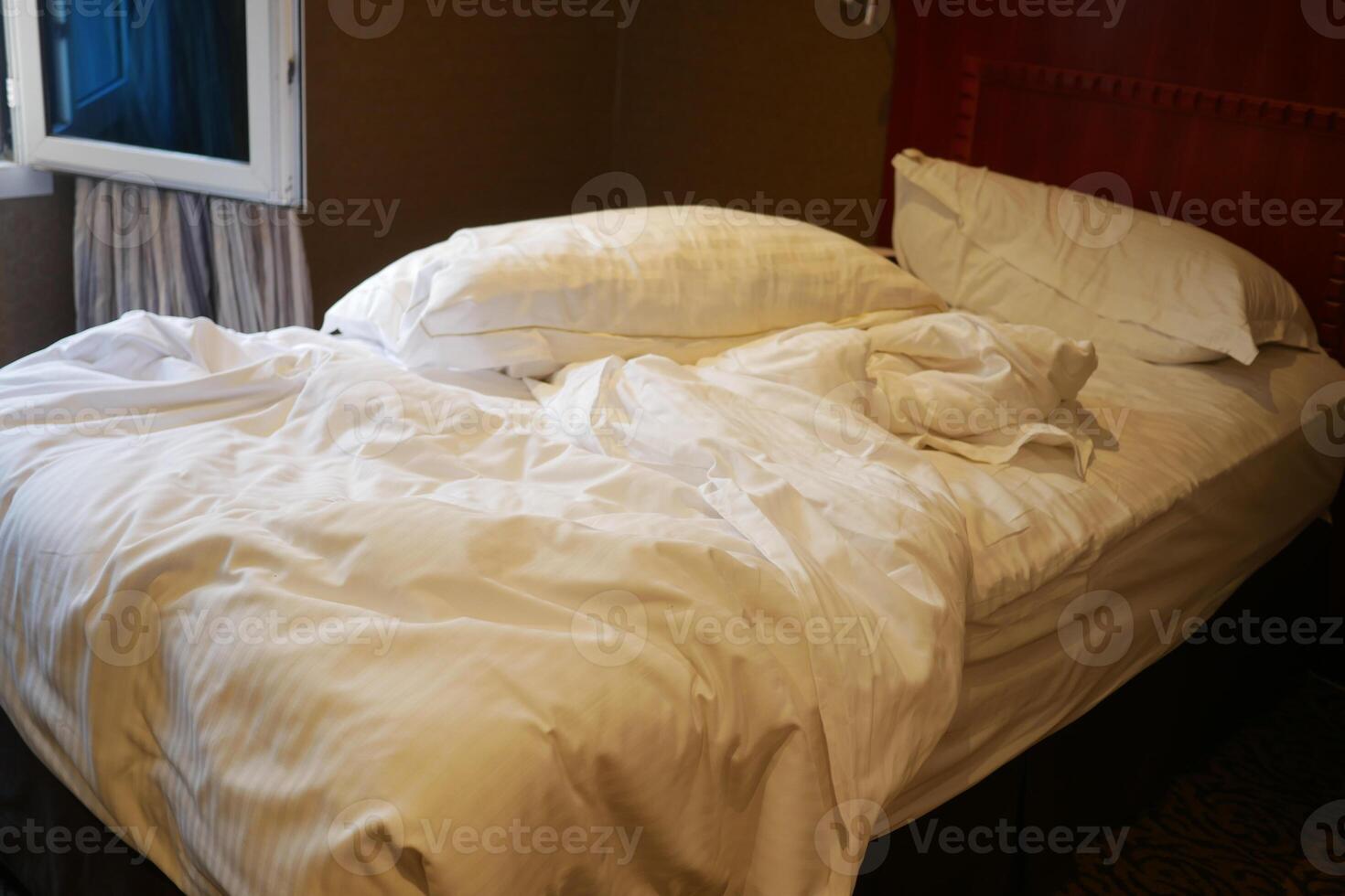 A messy white bed in a room at early morning , photo