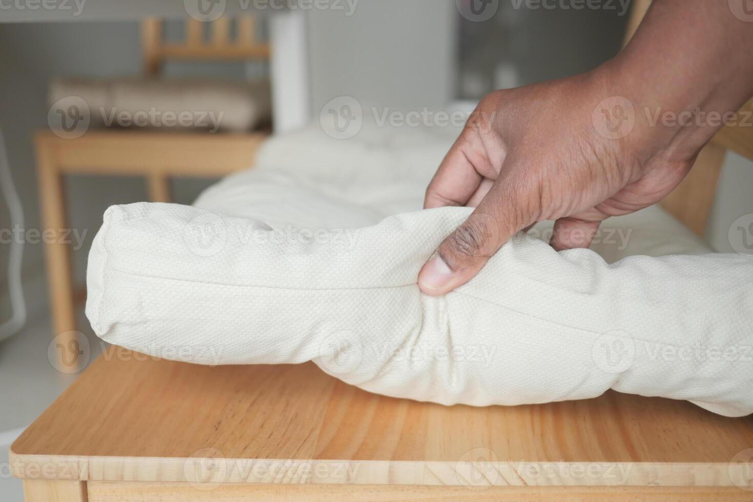Hand arranging a rolled cushion on a wooden table photo