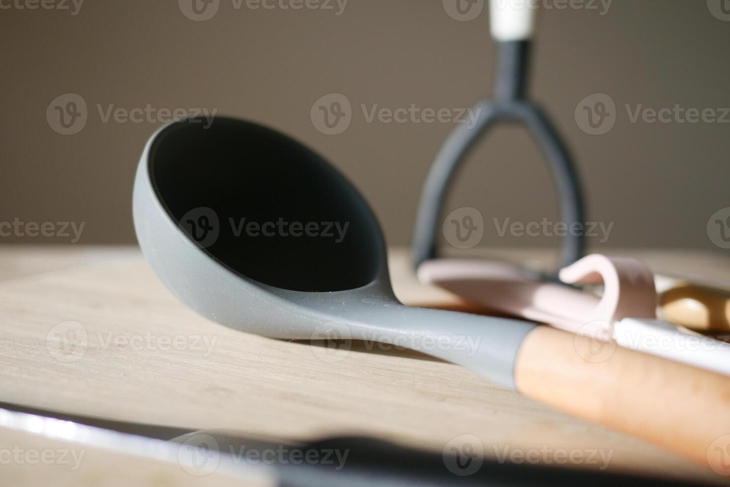 Kitchen utensils arranged on a wooden surface in soft lighting photo