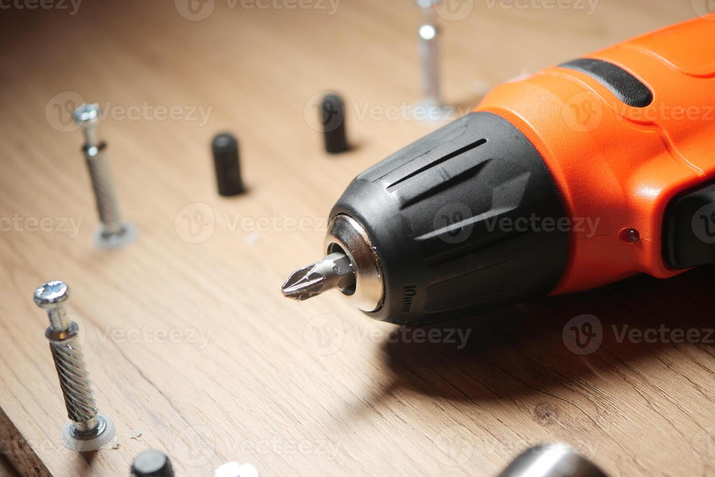 Power drill used for assembling furniture on a wooden surface photo