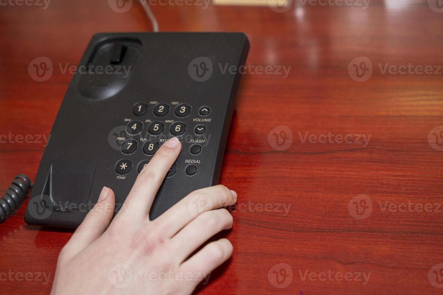close up woman hand pointing try to press button number on telephone office desk. High quality photo