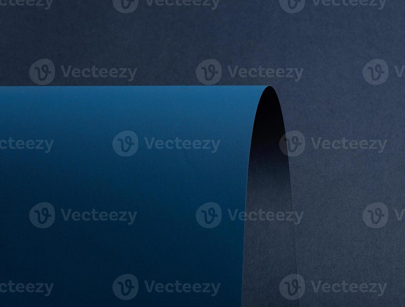 Paper background with matte texture. Curved smooth sheets in navy, midnight blue, and deep blue photo