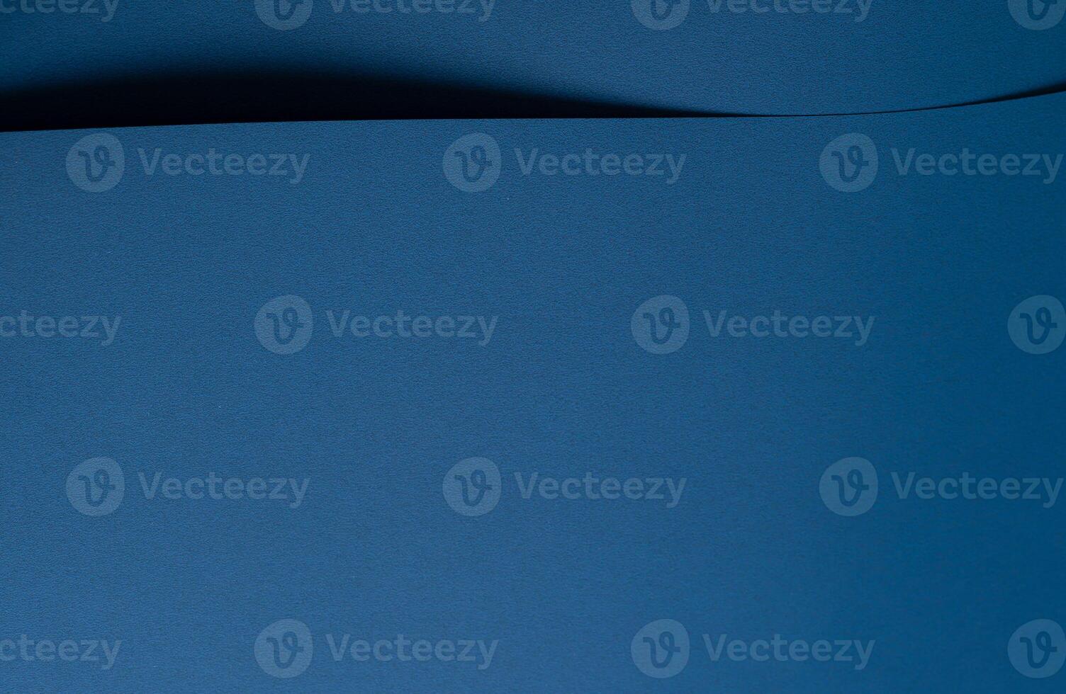 Paper background with matte texture. Curved wave and curl shape in ocean blue, royal blue, and deep photo