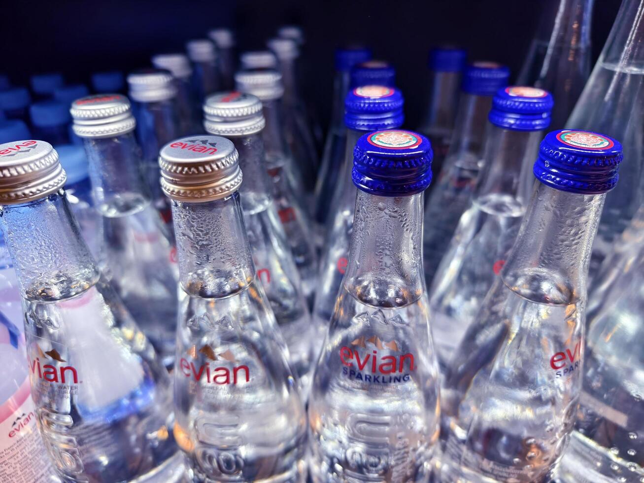 PHUKET, THAILAND - MARCH 8, 2025. Bottles of Evian mineral water are neatly lined up on a shelf photo