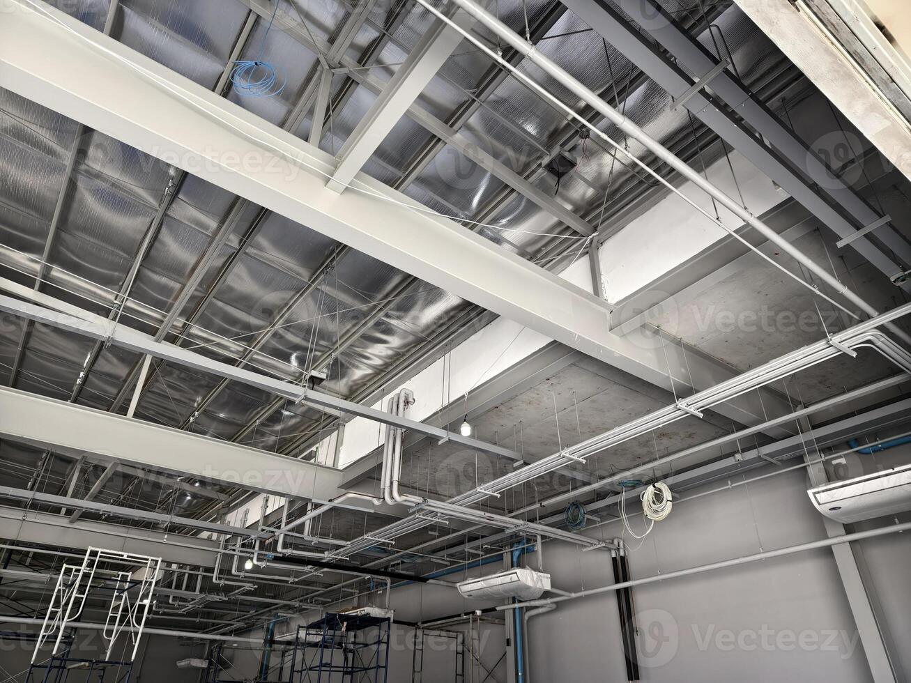 The ceiling of a large building under construction an extensive network of pipes photo