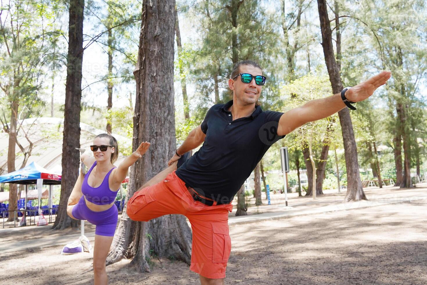 A man and a woman are engaging in stretching exercises together in a park photo