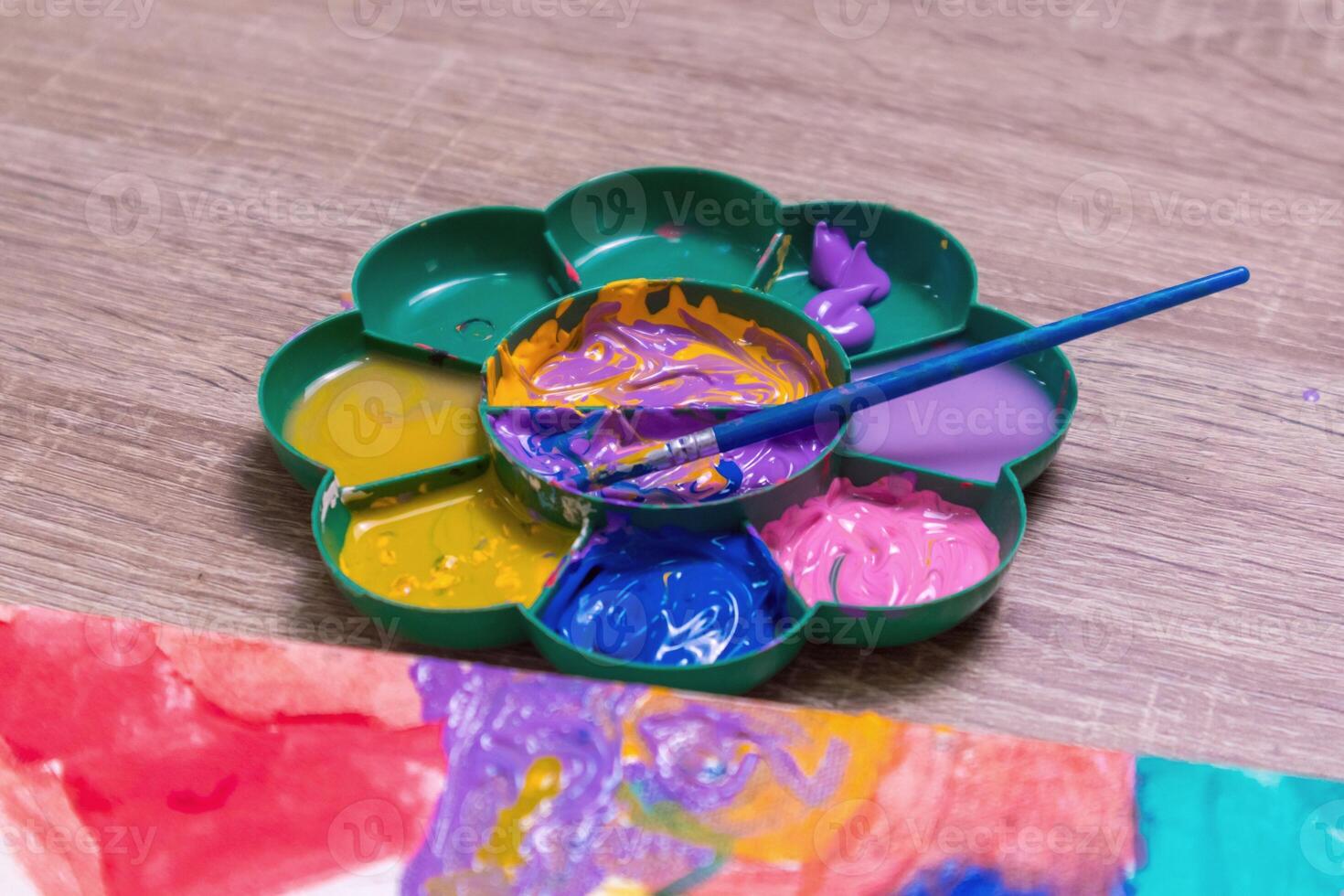 A paintbrush on a watercolor palette and canvas on the table photo