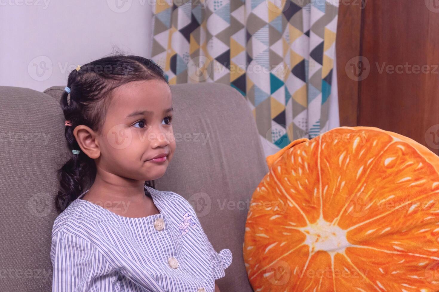 A cheerful little Asian girl relaxing on sofa at home photo