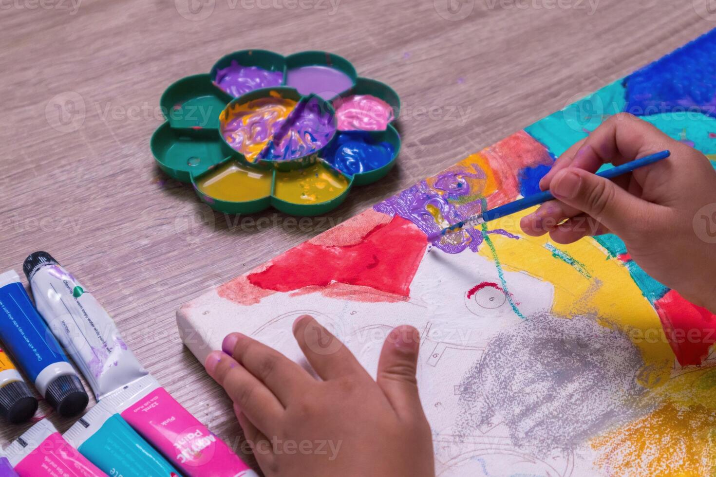 Close up view of little girl's hands painting on canvas on the table photo