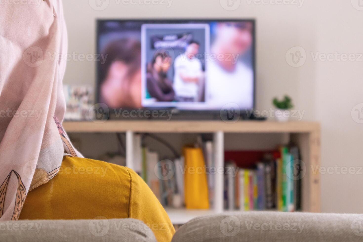 Asian Muslim woman relaxing on sofa while watching the TV at home photo