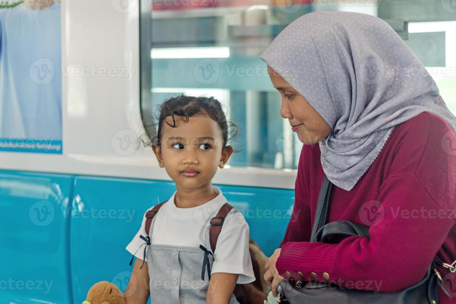 Asian Muslim mother and her little girl sitting on the train for travel photo