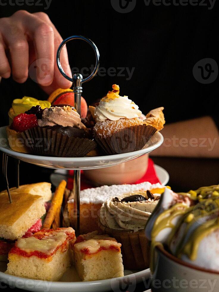 Selecting Pastries from a Tiered Stand photo