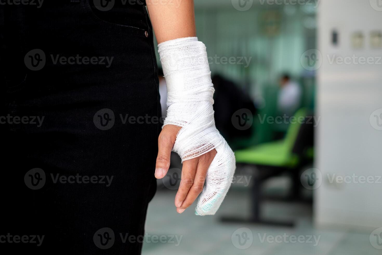 Injured hand wrapped in bandages after an accident, standing in a hospital waiting area. Medical emergency, healthcare, or workplace safety concept photo