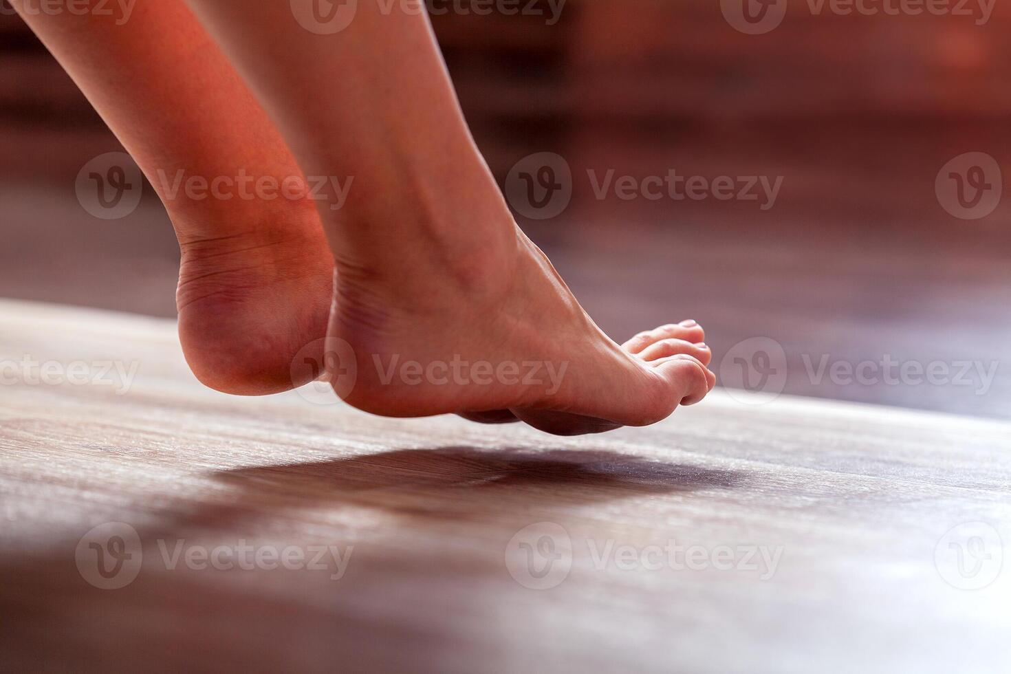 Legs of a young woman on a wooden floor, close-up photo