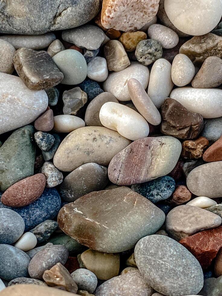High-quality close-up photo of colorful smooth pebbles on a beach. Natural rounded stones with detailed textures and soft daylight. Perfect for backgrounds, nature themes, or design use.