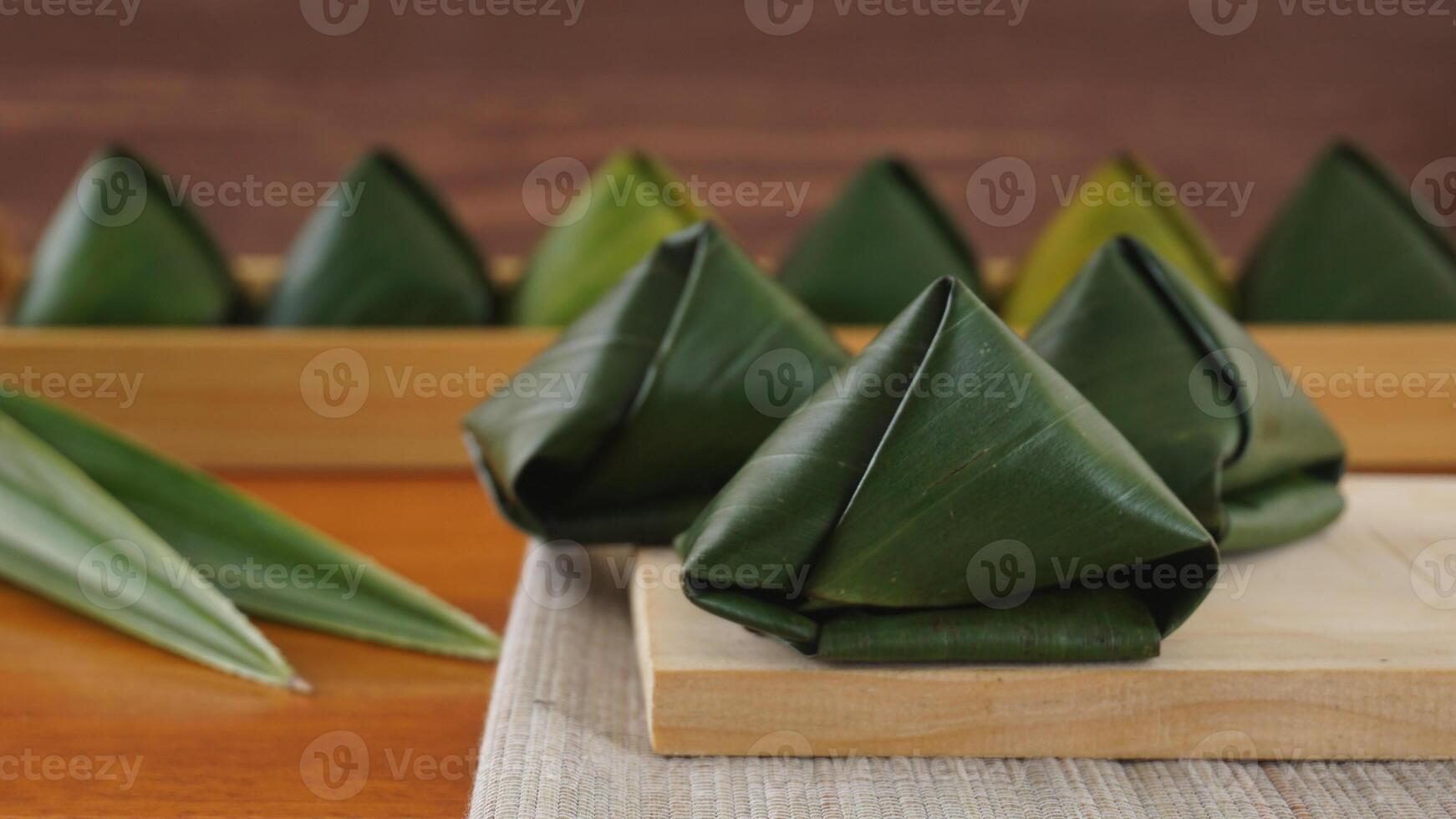 Kue Bugis, traditional Indonesian snack dessert wrap in green leaves called on wooden platter photo