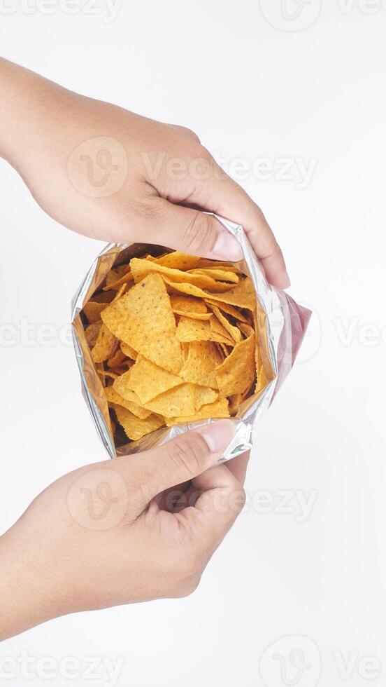 Man hands holding an opened foil bag of yellow tortilla chips isolated on white background photo