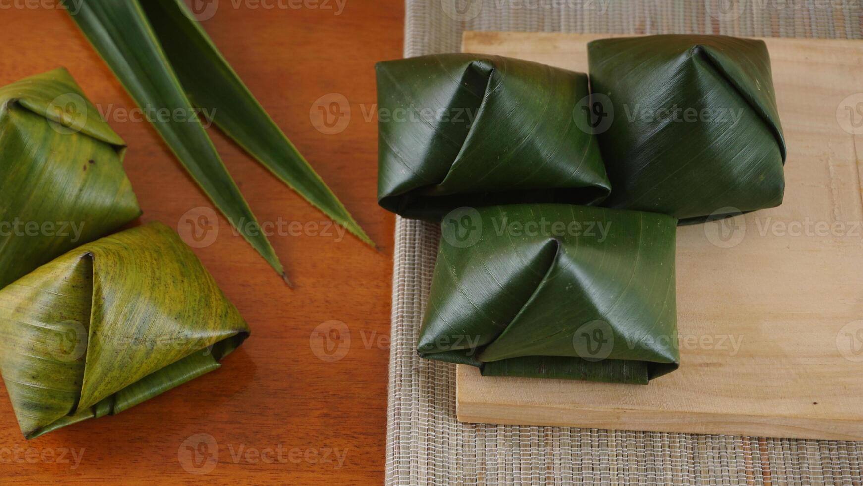 Kue Bugis, traditional Indonesian snack dessert wrap in green leaves called on wooden plate photo