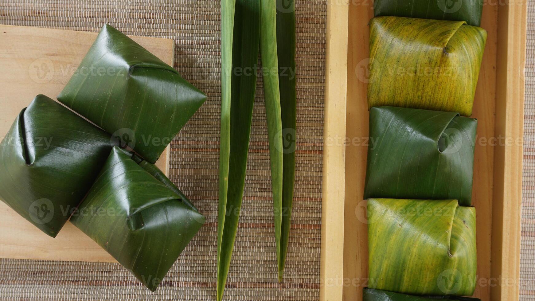 Top view of Kue Bugis, popular traditional Indonesian snack dessert wrap in green leaves called on wooden background photo