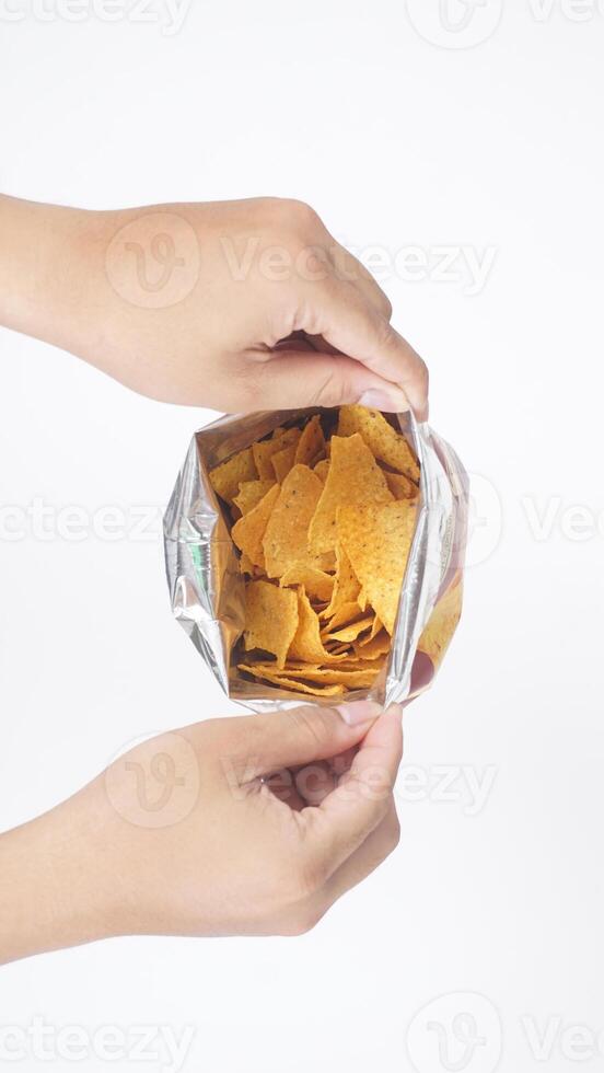 Man hands opened a foil bag of yellow tortilla chips isolated on white background photo