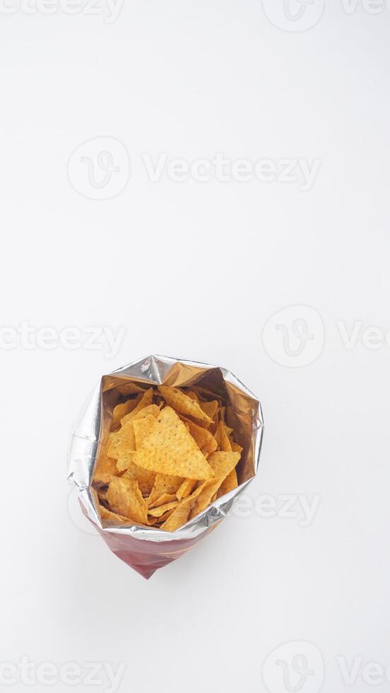 Yellow tortilla chips in opened foil bag isolated on white background photo