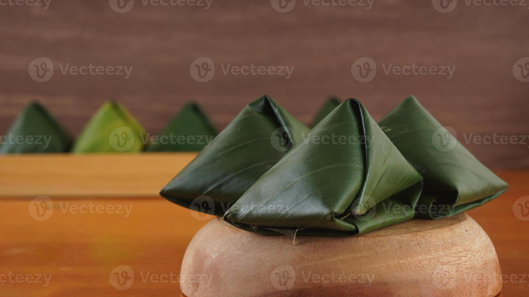 Traditional Indonesian snack dessert wrap in green leaves called Kue Bugis on wooden platter photo